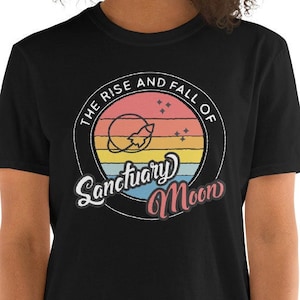 May include: Black t-shirt with a retro-style graphic of a planet with a crescent moon and stars. The text "The Rise and Fall of Sanctuary Moon" is written in a stylized font.