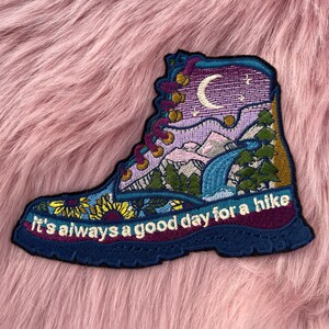 May include: Embroidered patch of a hiking boot with a mountain scene and the text "It's always a good day for a hike".