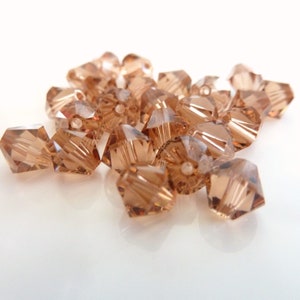 May include: A group of small, faceted, brown glass beads. The beads are shaped like a pyramid with a pointed top and a flat base.