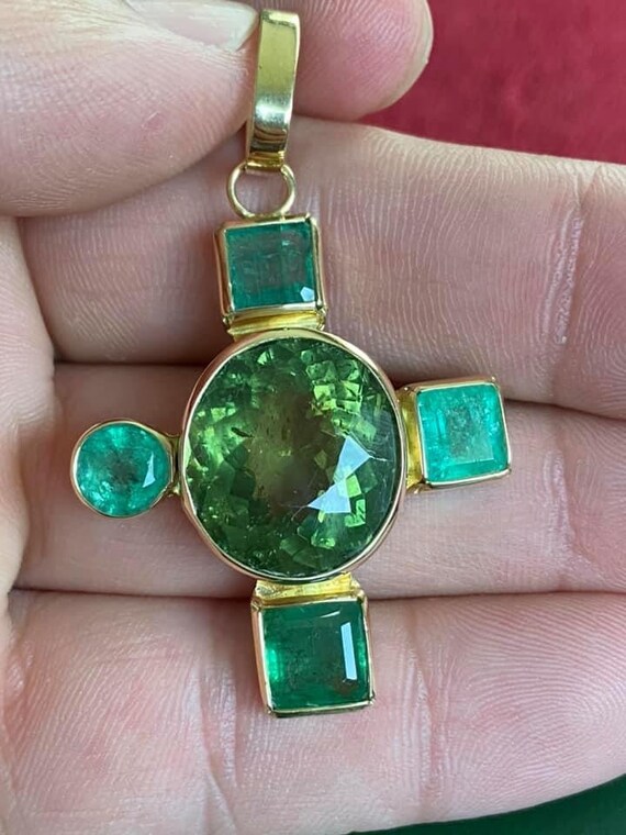 A large solid 18k gold cross set with emeralds and to… Gem