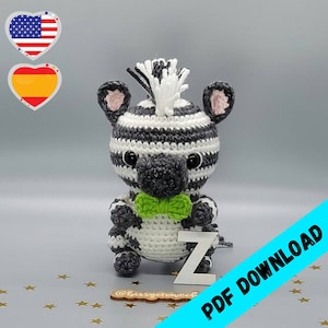 May include: A crocheted zebra toy with black and white stripes, wearing a green bow tie. The toy is sitting on a white surface with gold stars.