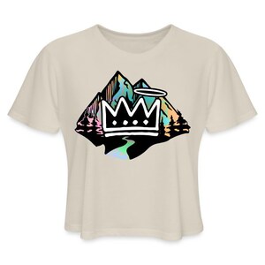 May include: A beige cropped t-shirt with a black and white graphic of a mountain range with a crown on top. The mountain range is filled with iridescent colors.