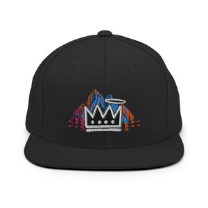 May include: Black baseball cap with a flat brim. The cap features an embroidered design of a white crown, a halo, and a colorful mountain range in shades of blue, orange, and pink.
