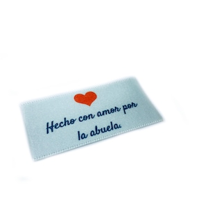 May include: A white fabric label with a red heart and the text "Hecho con amor por la abuela" in blue.