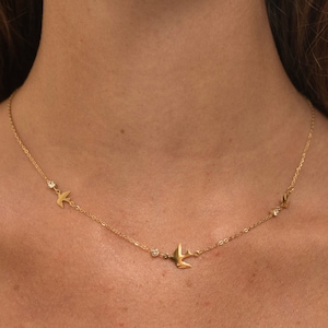 May include: A gold necklace with three small bird charms and three tiny clear stones.
