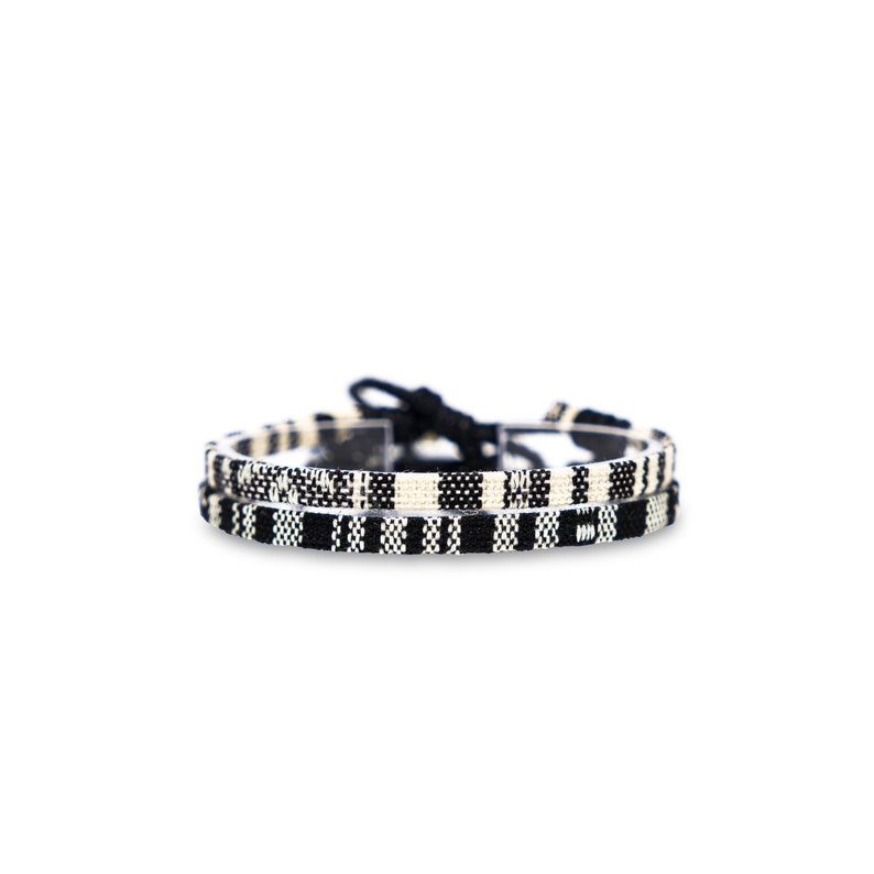 May include: Two black and white woven bracelets with a knot closure.