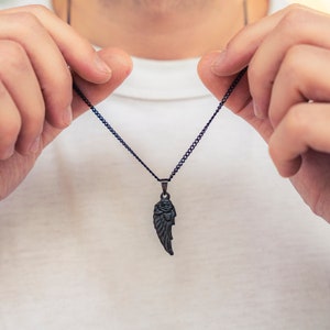 May include: A black chain necklace with a black metal wing pendant.