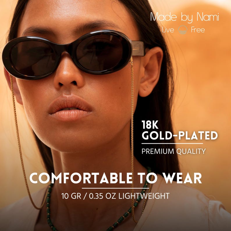 May include: A woman wearing black oval sunglasses with a gold chain attached to the frames. The chain is 18K gold-plated and the text "Made by Nami" is visible in the top right corner of the image. The text "Live Free" is also visible below the text "Made by Nami". The text "18K GOLD-PLATED" is visible in the bottom right corner of the image. The text "PREMIUM QUALITY" is visible below the text "18K GOLD-PLATED". The text "COMFORTABLE TO WEAR" is visible in the center of the image. The text "10 GR / 0.35 OZ LIGHTWEIGHT" is visible below the text "COMFORTABLE TO WEAR".