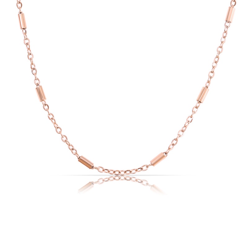 May include: A rose gold chain necklace with small, cylindrical beads.
