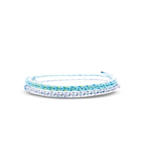 Puede incluir: Un conjunto de tres pulseras trenzadas en tonos azules, blancos y rosas. Las pulseras est&aacute;n hechas de un cord&oacute;n fino y tejido.