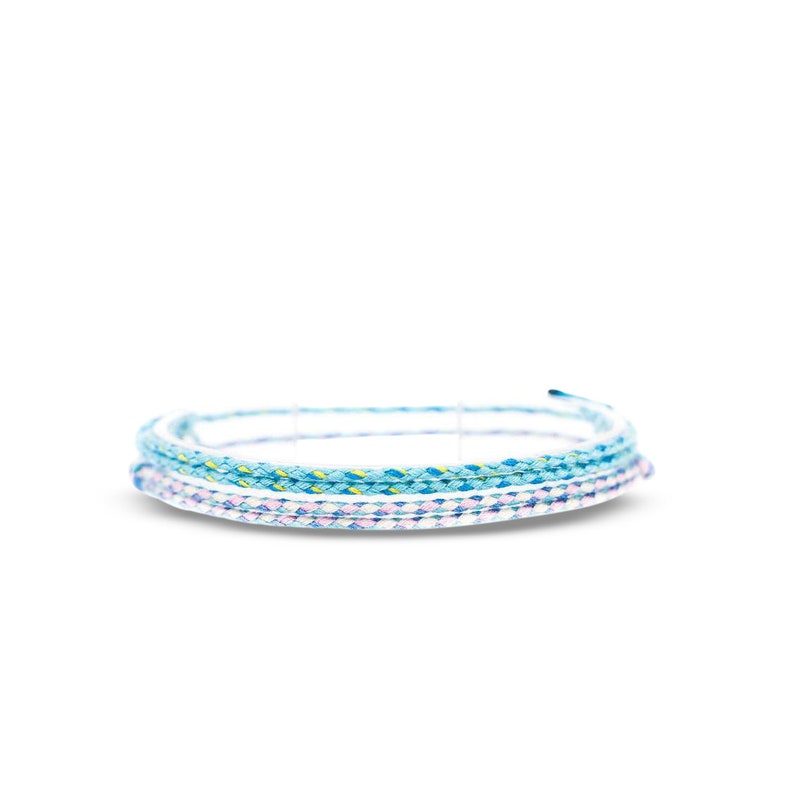 Puede incluir: Un conjunto de tres pulseras trenzadas en tonos azules, blancos y rosas. Las pulseras est&aacute;n hechas de un cord&oacute;n fino y tejido.