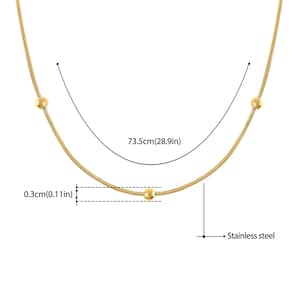 May include: A gold chain necklace with three small round beads. The necklace is 28.9 inches long and 0.11 inches wide. The chain is made of stainless steel.