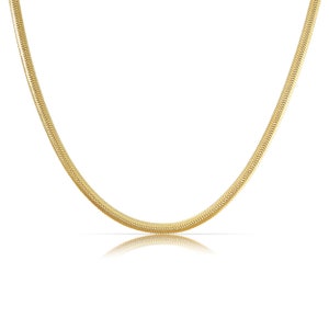 May include: A gold snake chain necklace. The chain is made of small, interlocking links that create a smooth, continuous surface.