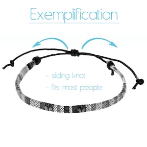 May include: A black and white woven bracelet with a sliding knot closure. The bracelet is adjustable to fit most people. "Exemplification" is written above the bracelet.