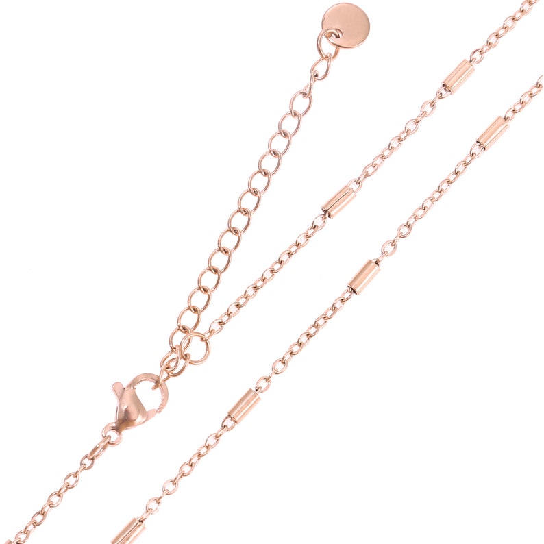 May include: A rose gold chain necklace with a lobster clasp and a small round disc at the end. The chain has a delicate design with small, round links.