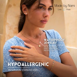 K&ouml;nnte beinhalten: Eine Frau tr&auml;gt ein blau-wei&szlig; gemustertes Hemd mit einer goldenen Halskette und einem goldenen Blumenanh&auml;nger. Sie tr&auml;gt auch ein Armband mit bunten Steinen. Der Text "WATERPROOF JEWELRY" ist in Schwarz auf wei&szlig;em Hintergrund geschrieben. Der Text "NO RUSTING OR DISCOLORATION, NEVER FADE" ist in Schwarz auf wei&szlig;em Hintergrund geschrieben. Der Text "HYPOALLERGENIC" ist in Schwarz auf wei&szlig;em Hintergrund geschrieben. Der Text "316 SURGICAL STAINLESS STEEL" ist in Schwarz auf wei&szlig;em Hintergrund geschrieben.