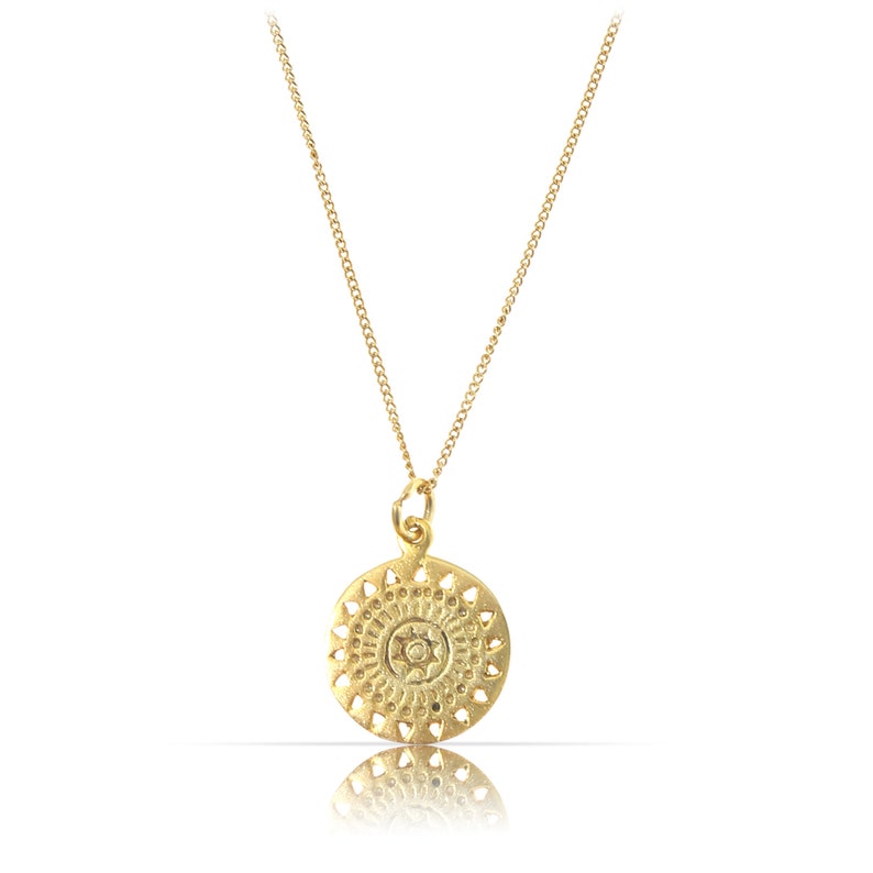 K&ouml;nnte beinhalten: Eine goldene Halskette mit einem runden Anh&auml;nger, der ein detailliertes Mandala-Design zeigt.