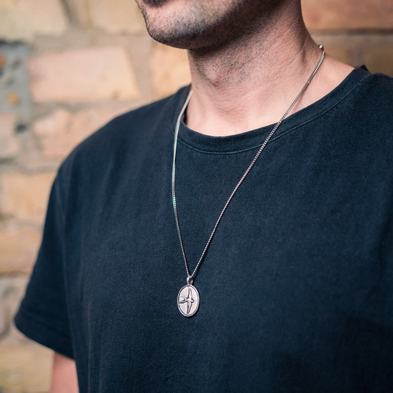 May include: A silver chain necklace with a round pendant featuring a stylized bird design.