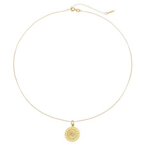 K&ouml;nnte beinhalten: Eine goldene Kettenkette mit einem zarten, runden Anh&auml;nger mit einem detaillierten, kreisf&ouml;rmigen Design.