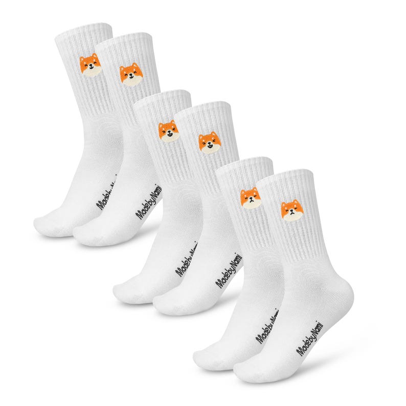 K&ouml;nnte beinhalten: Set von f&uuml;nf wei&szlig;en Socken mit einem Shiba Inu-Hundegesicht auf jeder Socke. Die Socken haben den Text "MadebyNomi" auf der Unterseite jeder Socke.
