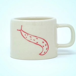 May include: A white ceramic mug with a red hand-painted illustration of a slug with dots. The mug has a rounded handle.