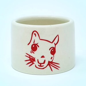 May include: White ceramic mug with a red cartoon squirrel face illustration.