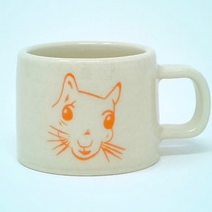 May include: A white ceramic mug with a cartoon squirrel face in orange on the front.