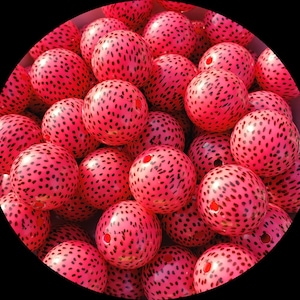 May include: A close-up of a group of pink and black polka dot beads. The beads are made of a smooth, glossy material and are perfect for crafting.