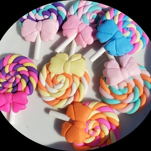 May include: Assortment of colorful swirl lollipop charms with bows. The lollipops are made of polymer clay and have a white stick.