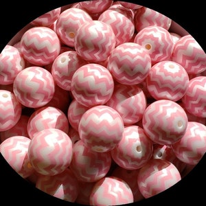 May include: A close-up of a group of pink and white silicone beads with a chevron pattern. The beads are round and have a glossy finish.
