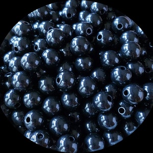 May include: A large group of black round beads with a hole in the center. The beads are shiny and have a smooth surface.