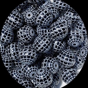 May include: A collection of black and white round beads. Each bead is decorated with a white spiderweb design. The beads are spherical and have a glossy finish. These beads are suitable for jewelry making and craft projects.