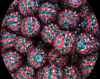 May include: A close-up of a group of red, green, and silver sparkly round beads. The beads are all the same size and are arranged in a random pattern.