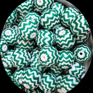 May include: A collection of green and white wooden beads with a chevron pattern. The beads are round and have a glossy finish.