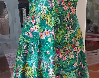 May include: A green dress with a floral print featuring pink, yellow, and white flowers. The dress has a v-neckline and cap sleeves.