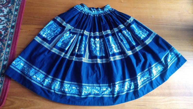 May include: A full blue skirt with a white and blue patterned design. The skirt has a gathered waist and a full, flowing silhouette.