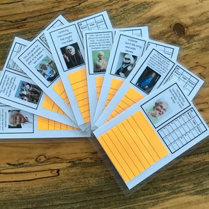 May include: A set of cards with different images and text on them. The cards are laid out in a fan shape on a wooden surface. The text on the cards includes quotes and names.