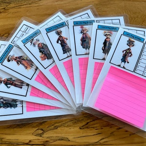 May include: A set of eight cards with a pink sticky note. The cards are printed with black and white illustrations of a woman in a dress and the text "Let's Play Budget!" and "I Can Play Budget!" The cards are in clear plastic sleeves.