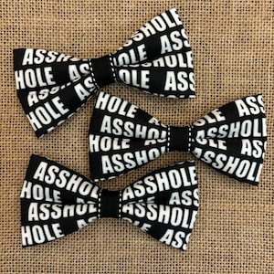 May include: Three black bow ties with a white repeating pattern of the word "ASSHOLE".