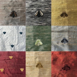 Può includere: Nove campioni di tessuto con motivi di falena ricamati. I campioni sono disposti in una griglia 3x3. I campioni sono di vari colori, tra cui grigio, nero, oro, verde, blu e rosso.