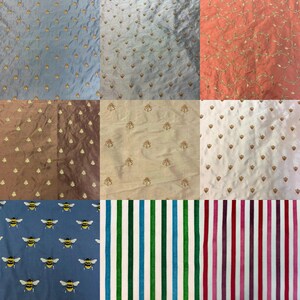 May include: Nine fabric swatches with various patterns and colors. Includes blue, brown, and white fabrics with gold embroidered details. Also features blue fabric with bee patterns, and striped fabrics in green, blue, pink, and purple.