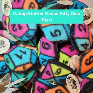May include: A close-up of a pile of colorful fleece kitty dice toys. The dice are filled with catnip and have numbers on each side. The toys are labeled "Kitty Dice".