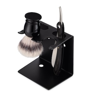 May include: A black metal stand with three slots for holding a shaving brush, razor, and other grooming tools. The stand has a black finish and a modern design.