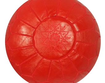 May include: A round, red leather pouf with a stitched geometric pattern. The center features an embroidered snowflake design. The pouf is a vibrant shade of red and appears to be made of high-quality leather.