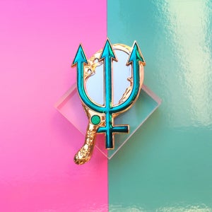 May include: Gold-tone pin with a green trident design and a white mirror-like surface. The pin is on a pink and blue background.