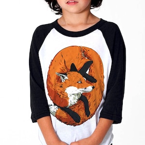 May include: A white and black baseball tee shirt with a graphic of an orange fox curled up sleeping. The fox is on the front of the shirt.