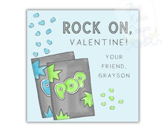 May include: A light blue Valentine's Day card with the text "ROCK ON, VALENTINE!" and "YOUR FRIEND, GRAYSON." It features two gray candy wrappers with the word "POP" in green. Blue and green accents complete the design.