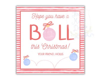 May include: A square Christmas card with a pink and white striped border. The card features the text "Hope you have a BALL this Christmas!" in pink script and block letters, with a pink and blue ornament illustration.