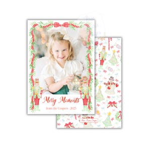 May include: Christmas card with a child holding a snow globe, surrounded by a red ribbon and green garland border. The card says "Merry Moments from the Coopers 2025." The reverse side has a repeating pattern of festive Christmas imagery.