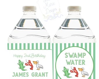 May include: Two green and white striped water bottle labels with a swamp theme. One label says "Happy 2nd Birthday James Grant" with a cartoon alligator, lobster, and pelican. The other label says "Swamp Water" with the same cartoon animals.